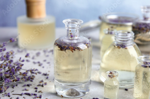 Fototapeta Naklejka Na Ścianę i Meble -  Bottles with natural herbal oil and lavender flowers on color table, closeup