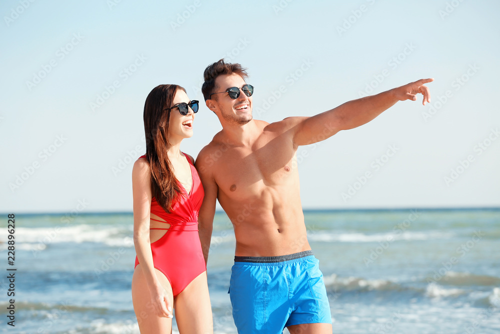 Happy young couple walking together on beach Happy young couple walking together on beach