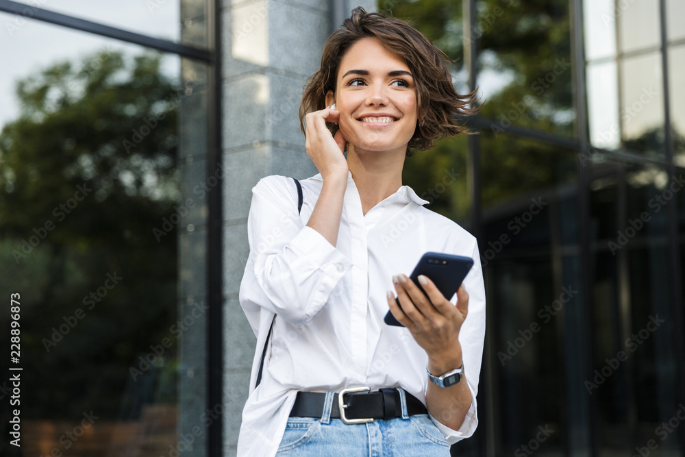 Happy young woman in earphones standing outdoors Happy young woman in earphones standing outdoors