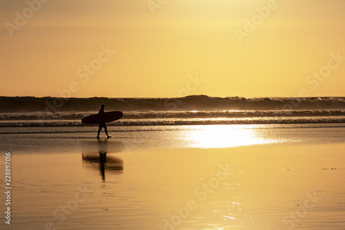 Silhouette of surfer and surfboard during sunset in Seminyak beach, Kuta, Bali, Indonesia. © cn0ra