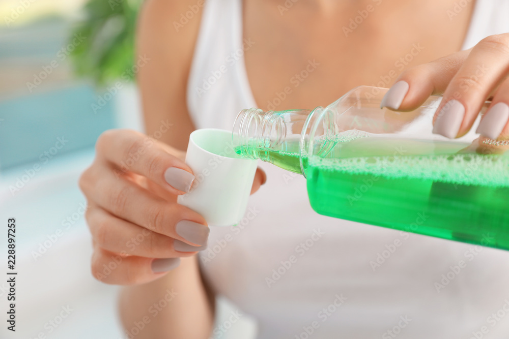 Woman pouring mouthwash from bottle into cap, closeup. Teeth care - obrazy, fototapety, plakaty 