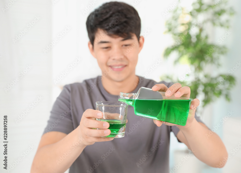 Man pouring mouthwash from bottle into glass. Teeth care Man pouring mouthwash from bottle into glass. Teeth care