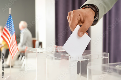 Man putting ballot paper into box at polling station, closeup