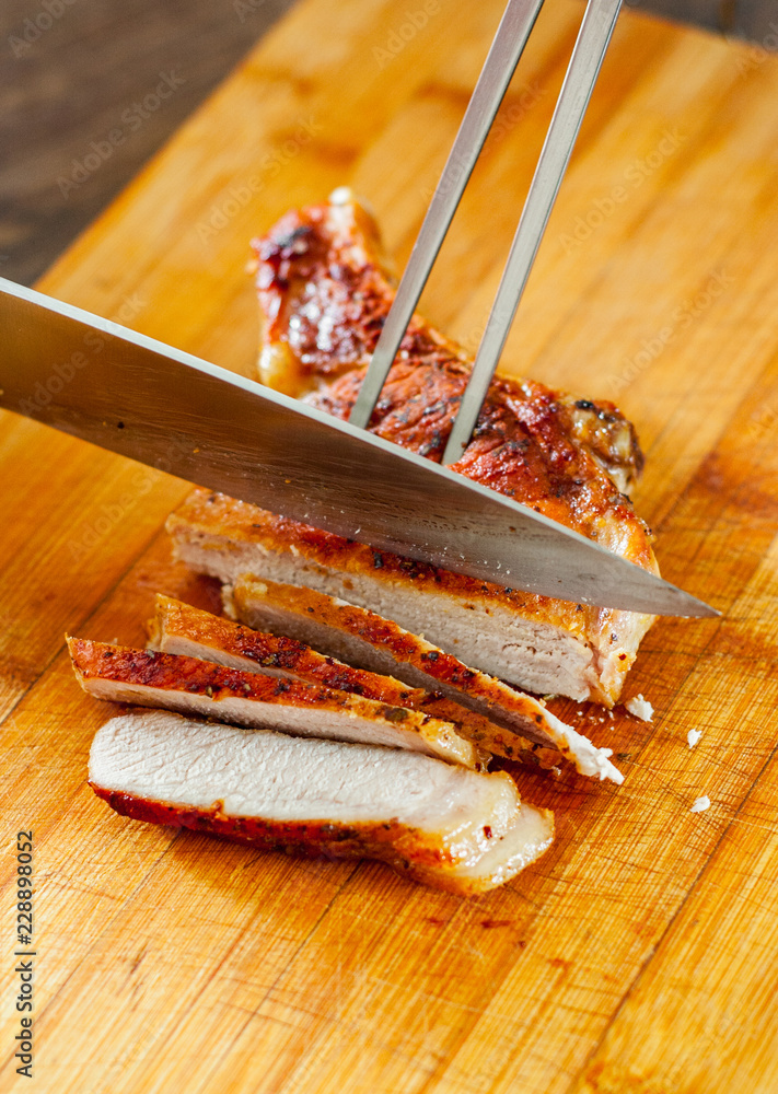 Fototapeta premium Chef hand with knife cutting meat on wooden board.