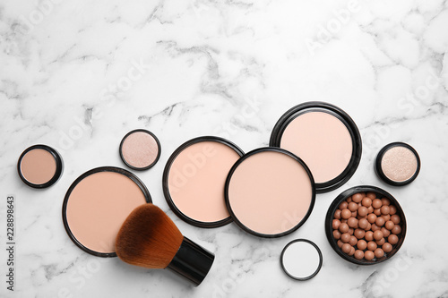 Flat lay composition with various makeup face powders on marble background. Space for text