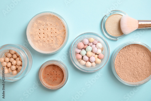 Flat lay composition with various makeup face powders on color background
