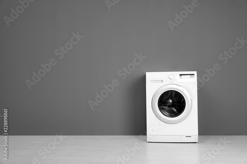 Empty washing machine near color wall, space for text. Laundry day