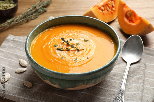 Delicious pumpkin cream soup in bowl on wooden table
