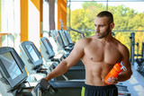 Portrait of athletic man with protein shake on treadmill in gym