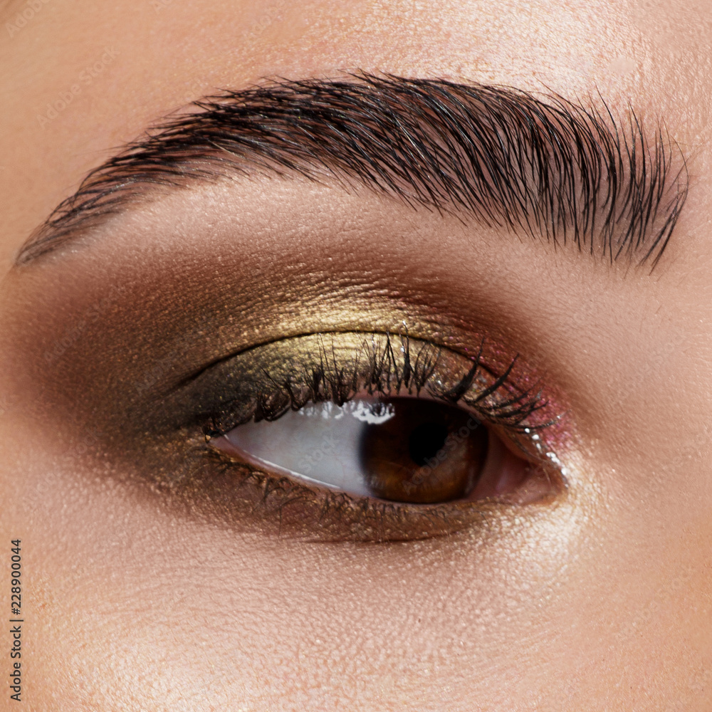 Obraz premium Zamknij się niebieskie oko kobiety z pięknym brązowym z odcieniami czerwieni i pomarańczy smokey eyes makeup. Nowoczesny makijaż.