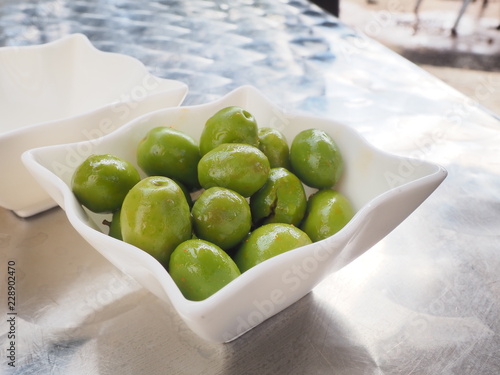 Olivas verdes con hueso servidas en bol blanco de cerámica.