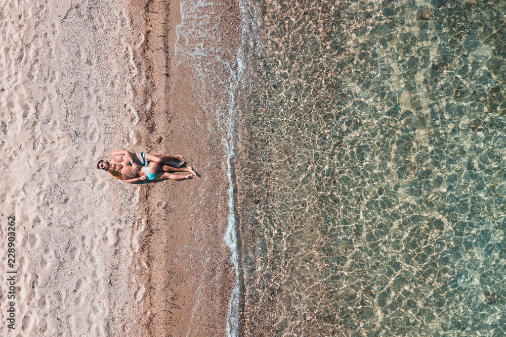 Fototapeta premium Aerial view on a young couple lying on the beach