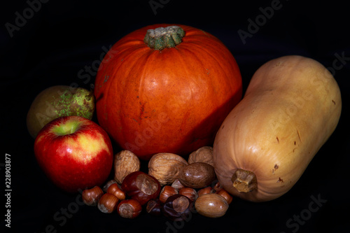 Autumn/Fall/Harvest vegetables, fruit and nuts against a black background.