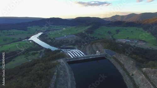 Backward flight away from huge pipes of Tumut hydroelectric Power Station at sunset - beautiful mountains scenery