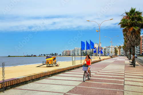 Woman biking on the boulevard along Pocitos beach in Montevideo, photo