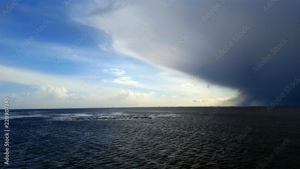 Obraz premium große graue Regenwolke über dem dunklen Meer am Horizont