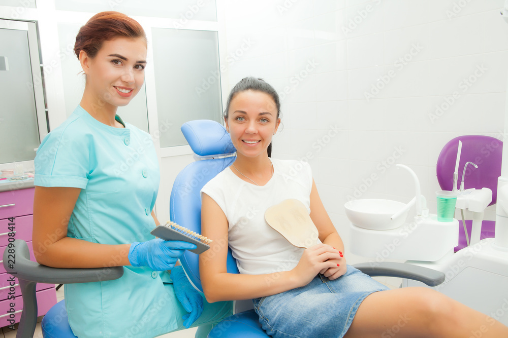 Fototapeta premium Beautiful female patient with dental treatment in the dentist office. A woman visiting her dentist. Women look into the camera