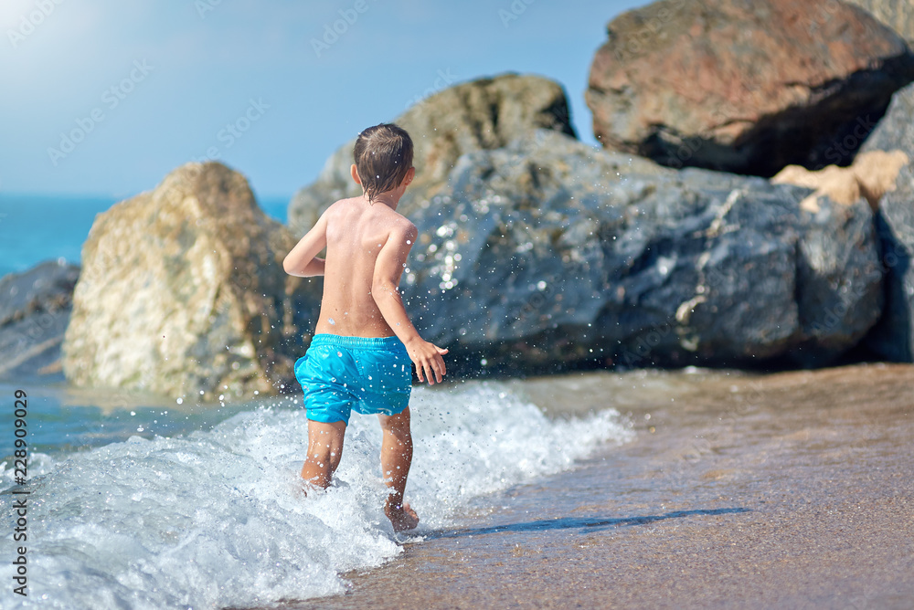 Cute Caucasian boy is running in the water along the sea shore. Cute Caucasian boy is running in the water along the sea shore.