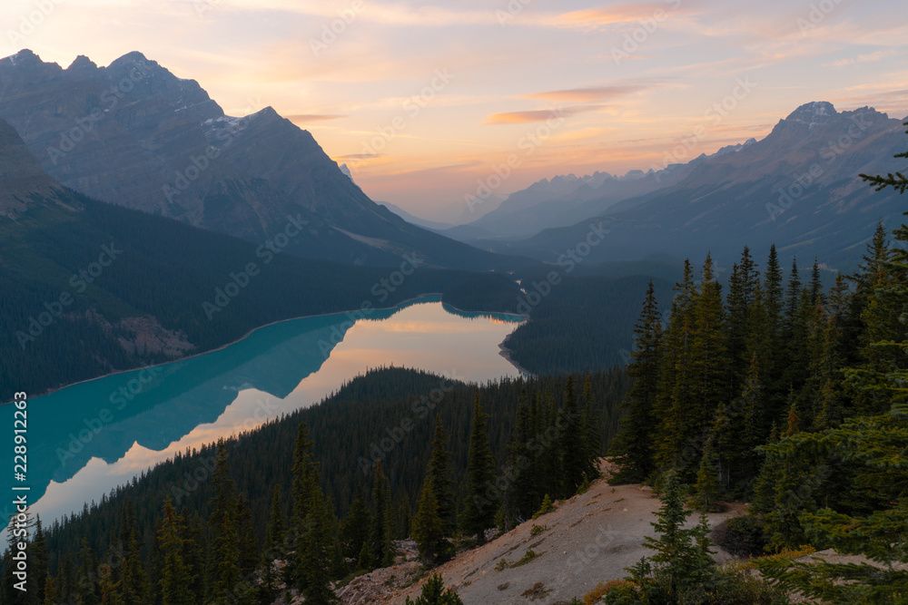 Obraz premium The orange glow of sunset over Peyto Lake in Banff National Park on a partly cloudy day