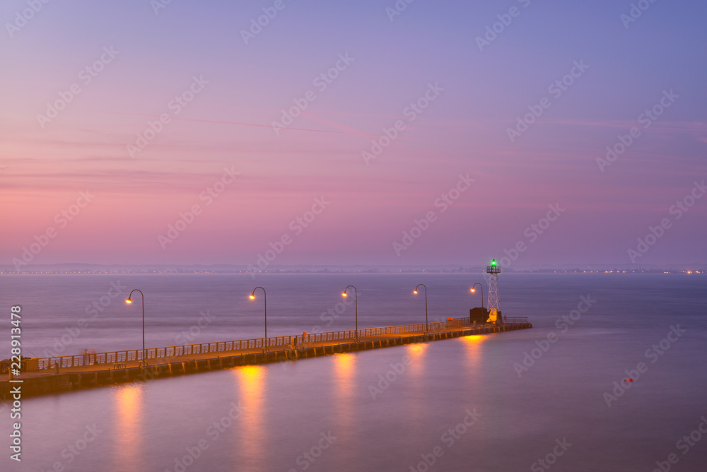 night lights above berth and green lighthouse in harbor in twilight time in France