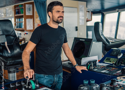 Marine navigational officer is maneuvering ship or vessel during navigation watch. He is using pitch and propulsion photo