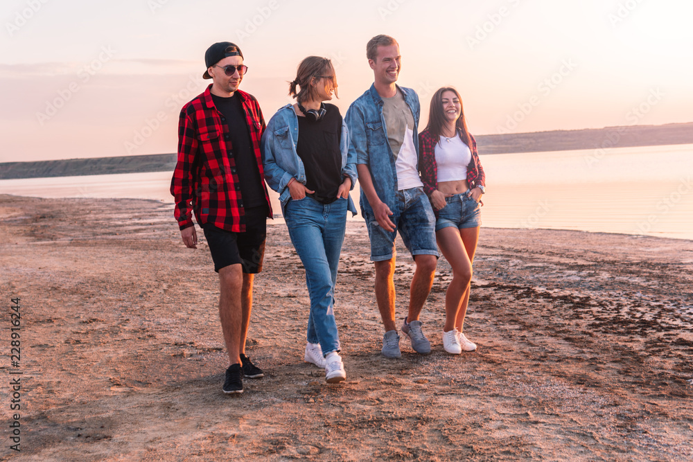 Group of hipster young friends on beach together walking during sunset. Freedom and friendship concept Group of hipster young friends on beach together walking during sunset. Freedom and friendship concept