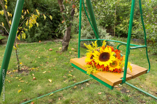 Fototapeta Naklejka Na Ścianę i Meble -  Autumn bouquet of sunflowers on a swing.