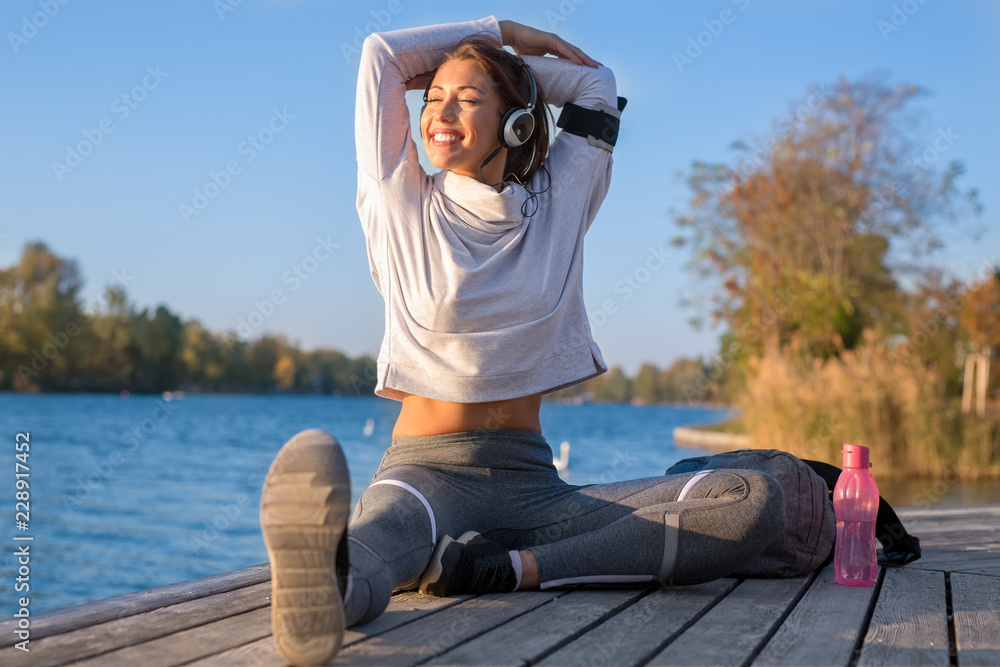 Beautiful young woman working out outside by the water