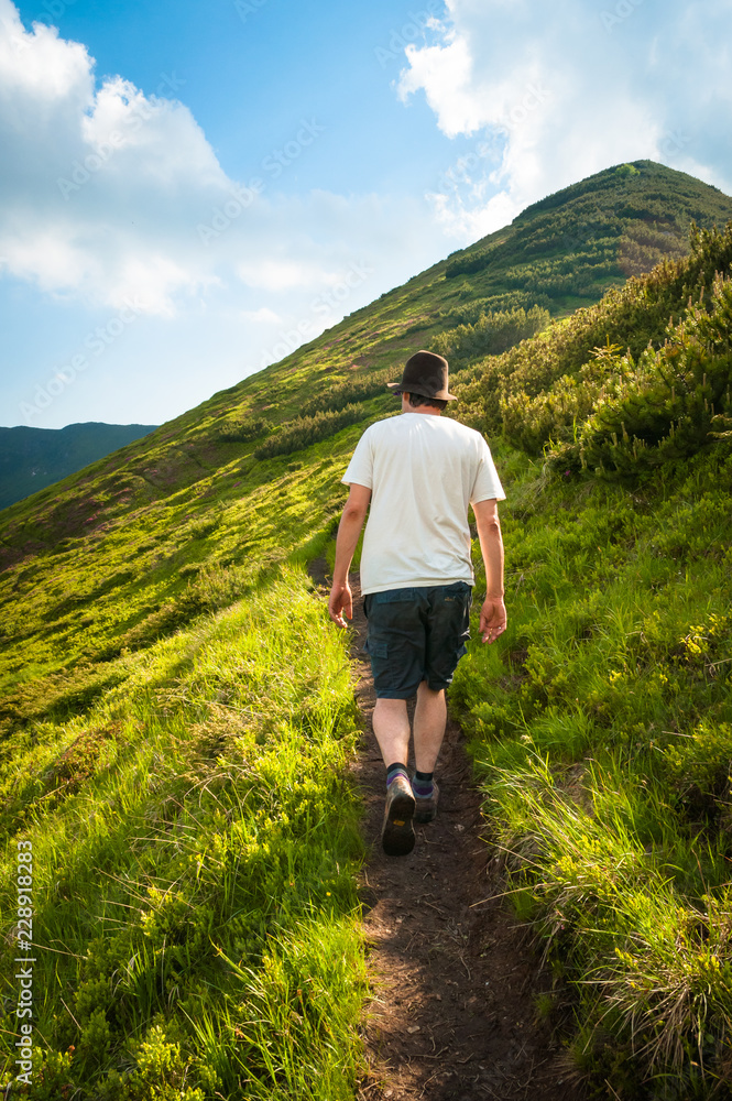 Man with white t-shirt and hat walking in the mountains Man with white t-shirt and hat walking in the mountains