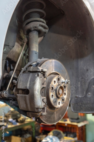 Disc brake of the vehicle for repair, in process of new tire replacement. Car brake repairing in garage.Close up.
