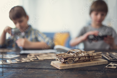 Close up of interesting detailed model of wooden car with two boys sitting in the background