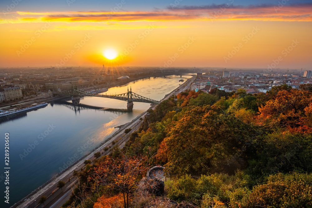 Budapest, Hungary - Panoramic skyline view of Budapest with beautiful autumn foliage, Liberty Bridge (Szabadsag Hid) and lookout on Gellert Hill and colourful sky at sunrise