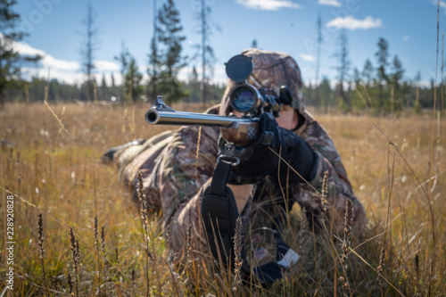 A Hunter In Camouflage Aiming a Scope and Rifle Close Up