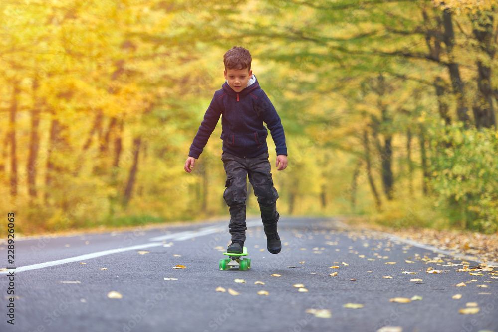 Fototapeta premium Kid skateboarder doing skateboard tricks in autumn environment