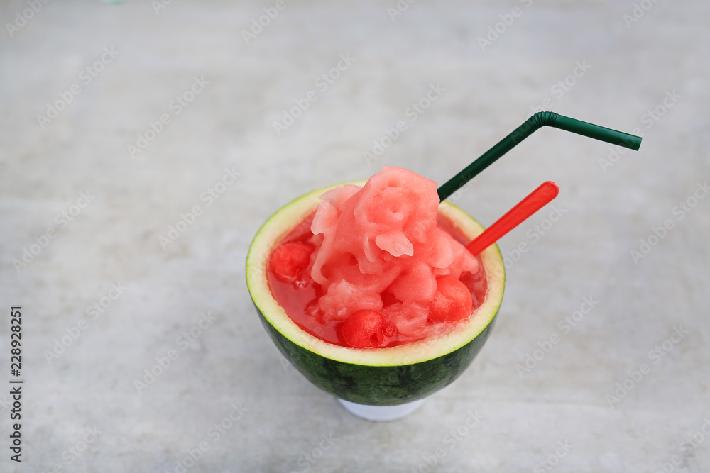 Fresh watermelon smoothie served in cut half watermelon shell place on stone table