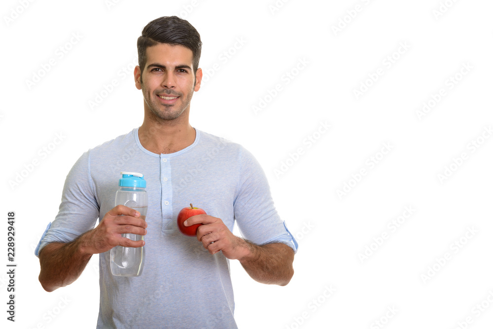 Young happy Persian man smiling and holding water bottle and red Young happy Persian man smiling and holding water bottle and red