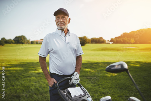 Senior man standing with his clubs on a golf course