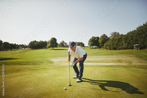 Senior man preparing to putt on a golf green