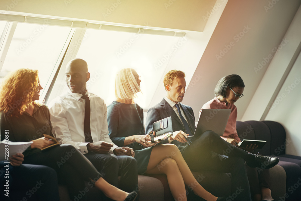 Diverse group of smiling businesspeople sitting on an office sof Diverse group of smiling businesspeople sitting on an office sof