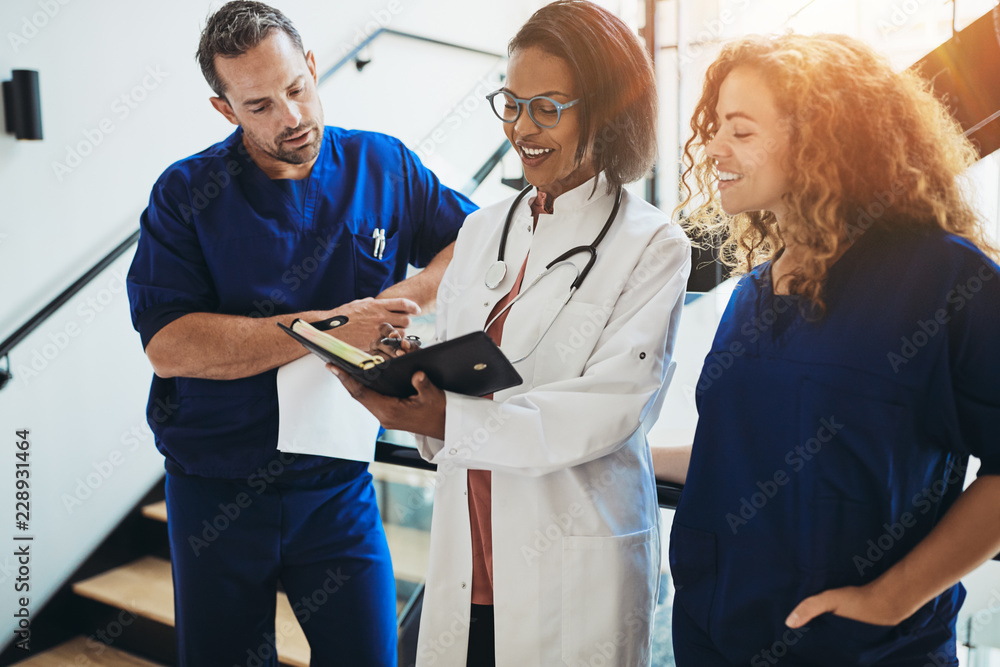 © Flamingo Images - Diverse doctors discussing paperwork together in a hospital corr © Flamingo Images - Diverse doctors discussing paperwork together in a hospital corr
