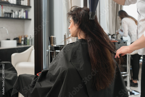 Professional hairstylist drying woman's hair in beauty salon