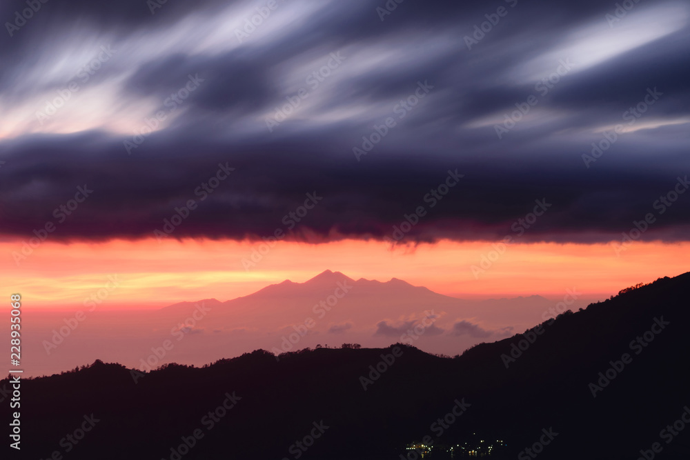Early sunrise view from Gunung Batur volcano in Bali, Indonesia with visible silhouette of Rinjani mountains Early sunrise view from Gunung Batur volcano in Bali, Indonesia with visible silhouette of Rinjani mountains