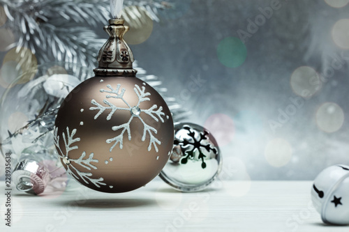 decorative glass balls and jingle bells for christmas tree on grey background with blurred fir tree branch
