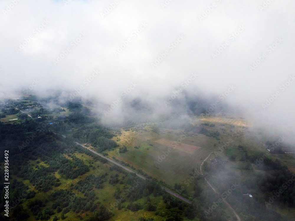 View of the countryside through the clouds in the summer with a drone