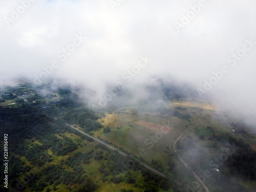 View of the countryside through the clouds in the summer with a drone © dmitriydanilov62