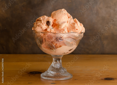 Rum and raisin icecream in glass bowl on rustic wooden table photo