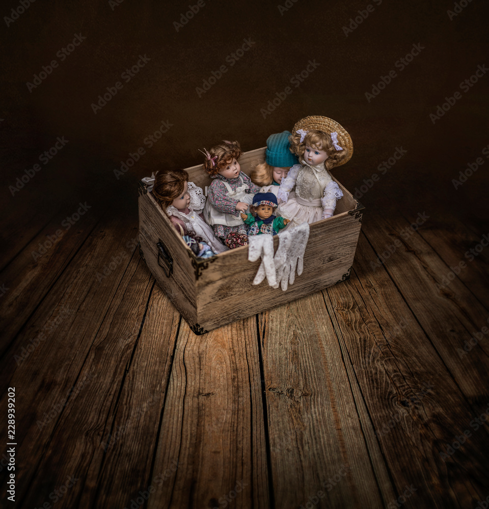 Fototapeta premium Variety dolls in a vintage box in dark empty room 