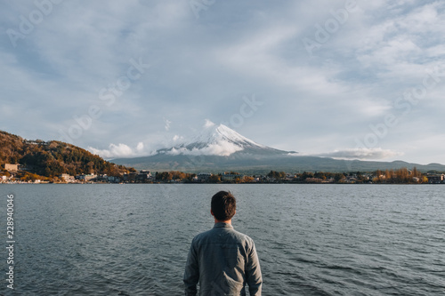 The male traveler stop to look at Mount fuji san at Lake kawaguchiko in japan on sunrise. Landmark of Japan