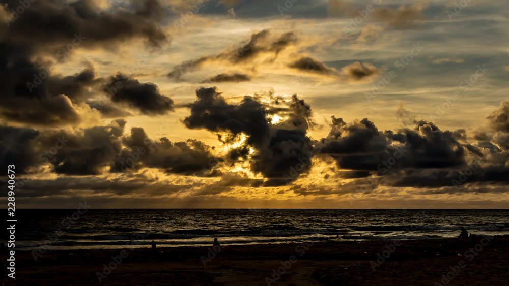 Dramatic clouds over the ocean as the sun sets and the sky turns dark, Karon Beach, Phuket Thailand.