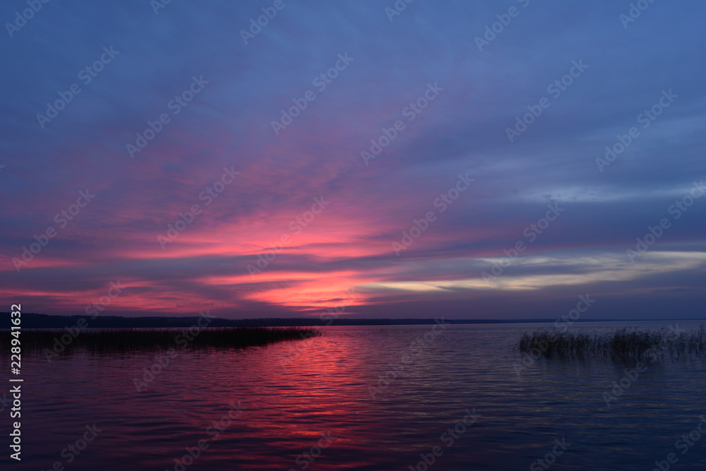 Twilight sky in bright colors sunset glowing above water surface the lake